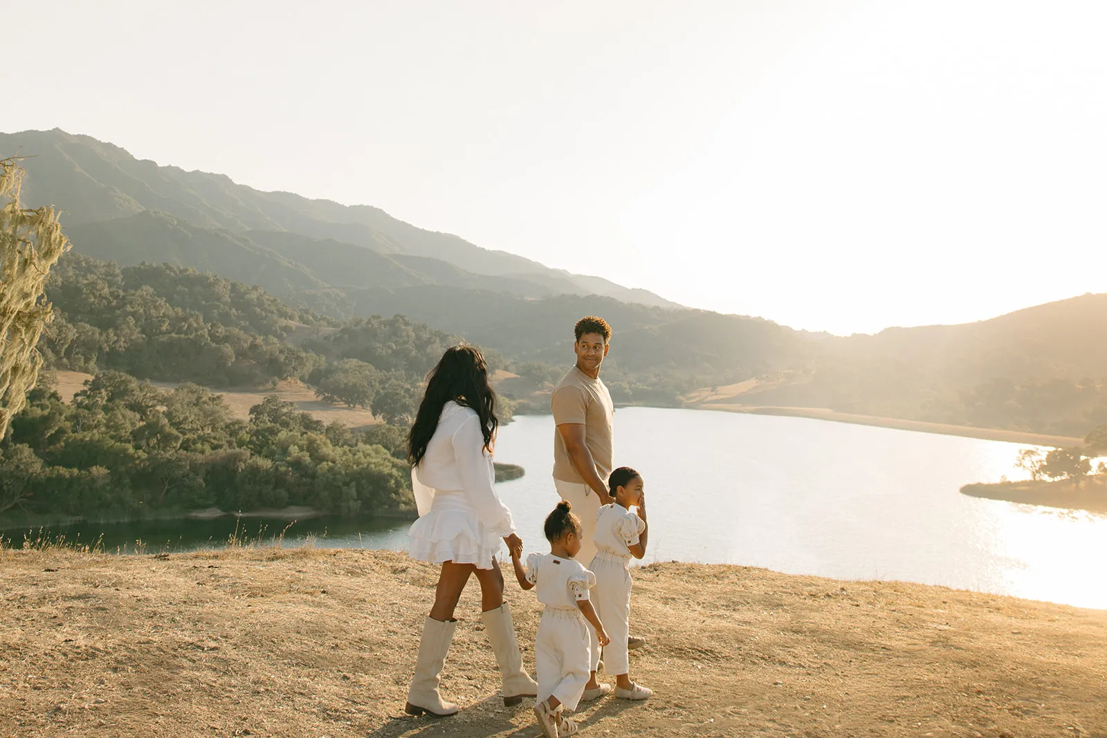 A family walking a golden hillside above a lake
