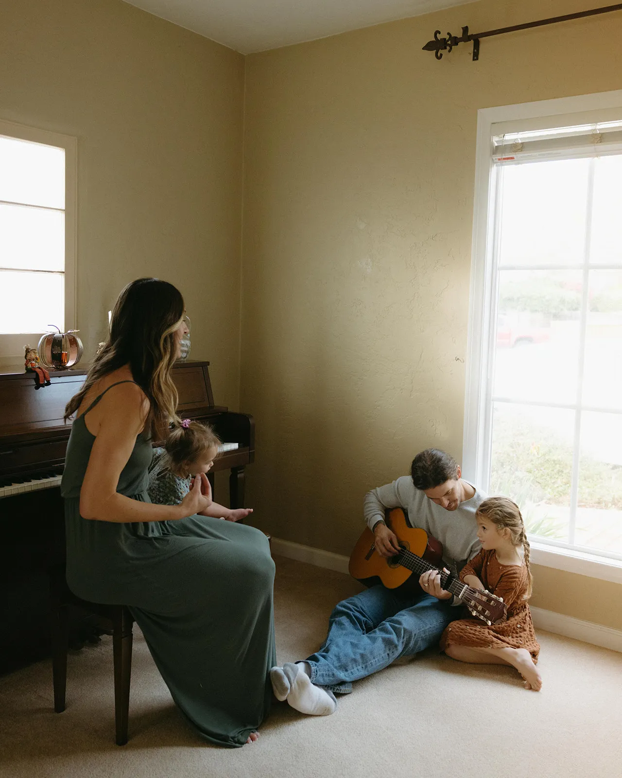 A mother at the piano while a father plays guitar on the floor