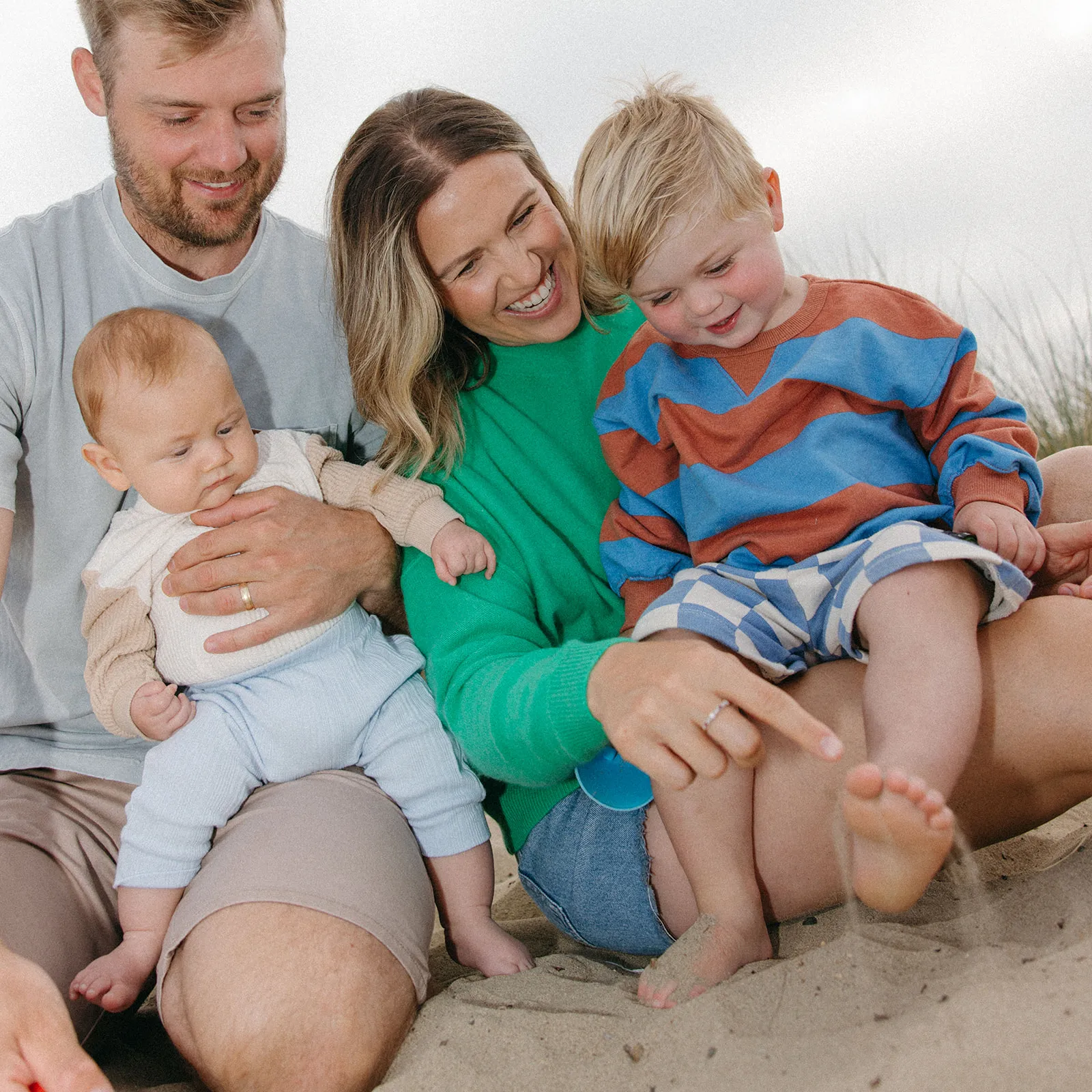 Parents sitting in the sand with their two young children