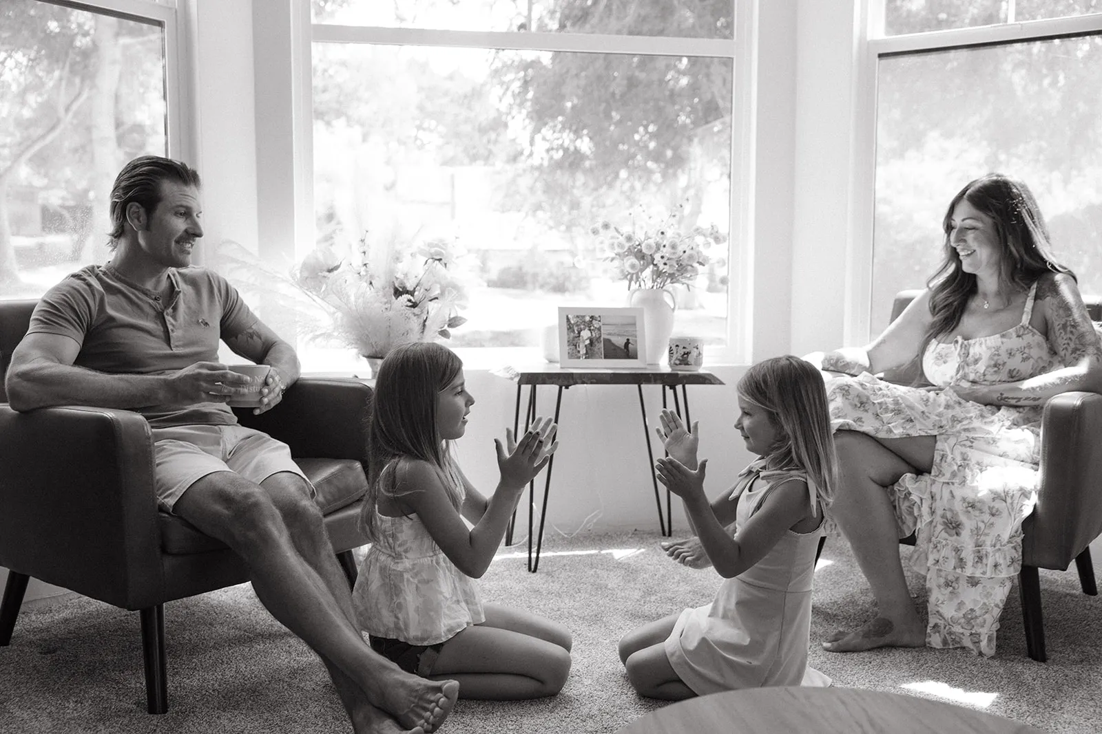 Two children playing a clapping game between their parents at home