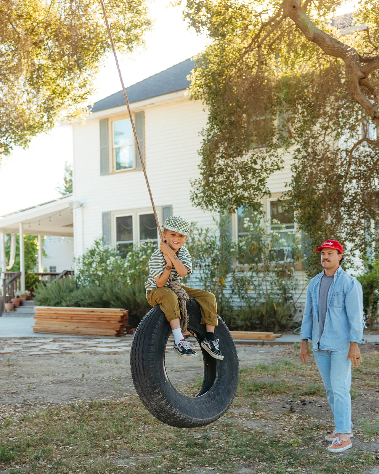 A child on a tire swing while their father looks on
