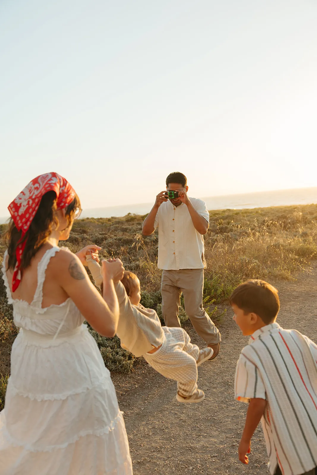 A mother and her children walking a golden hillside at sunset